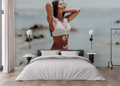 Beautiful latin woman with slim fit sexy body in bikini over beach background Wall mural